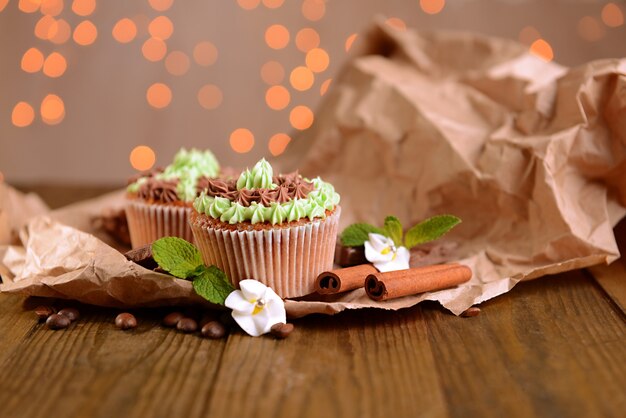 Leckere Cupcakes mit Buttercreme, auf Holztisch, auf Lichthintergrund