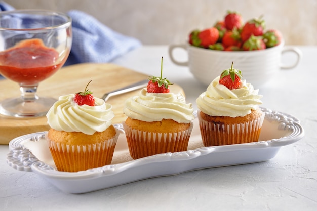 Leckere Cupcakes mit Erdbeeren und zarter Sahne auf weißem Hintergrund