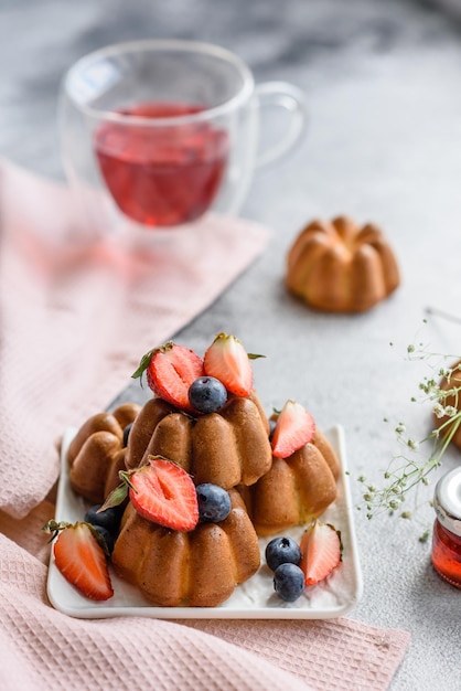 Leckere Cupcakes oder Muffins mit Rosinen und Nüssen, Erdbeeren und Blaubeeren