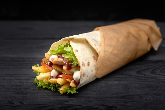 Leckere Döner-Kebabs mit frischem Salat und rasiertem gebratenem Fleisch, serviert in Tortilla-Wraps auf braunem Papier als Snack zum Mitnehmen