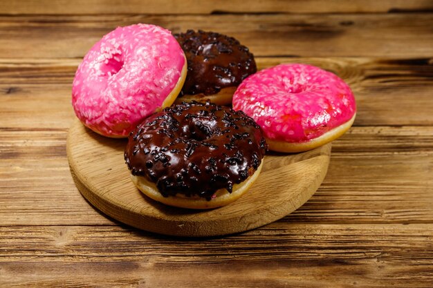 Leckere Donuts aus Rosa und Schokolade auf einem Holztisch