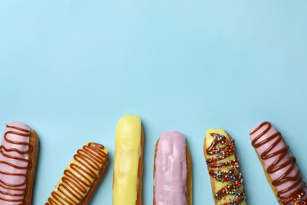 Leckere Eclairs mit unterschiedlichem Belag auf blauem Hintergrund