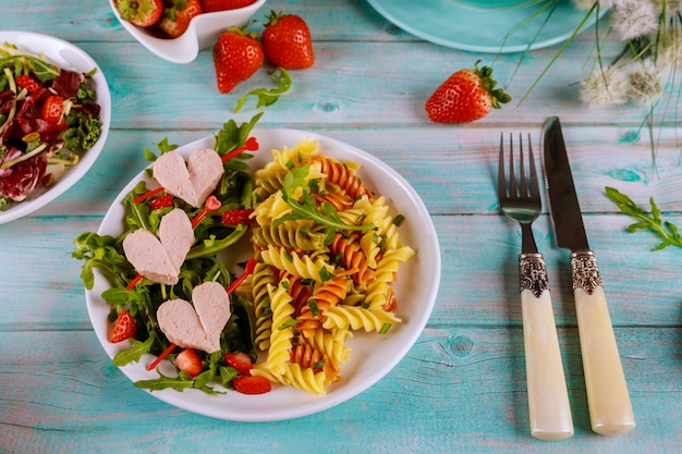 Leckere Farbe Rotini Pasta mit Würstchen, frische Erdbeere auf einer Holzoberfläche