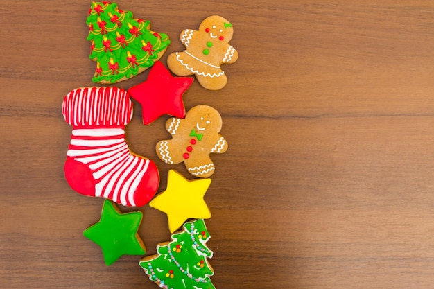 Leckere festliche Weihnachtsplätzchen in Form von Weihnachtsbaum, Lebkuchenmann, Stern und Weihnachtssocke auf Holztisch. Ansicht von oben