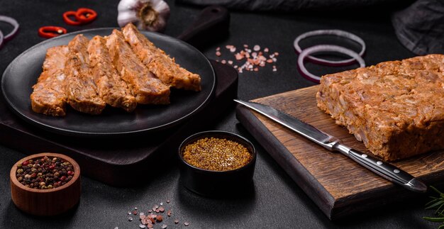 Leckere Fleischsülze oder Brötchen auf einem Holzschneidebrett mit Gewürzen und Kräutern