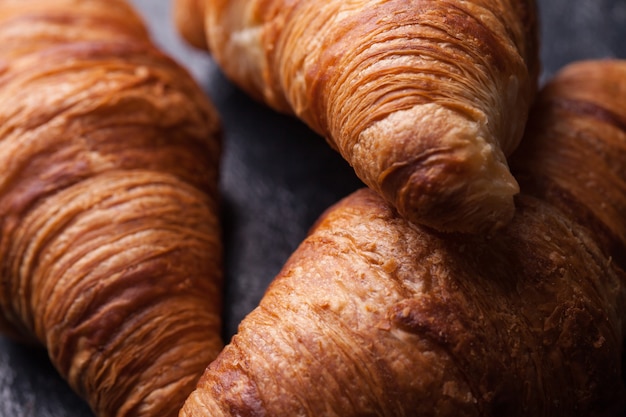 Leckere französische Croissants auf einem schwarzen Holztisch. Tolles Dessert