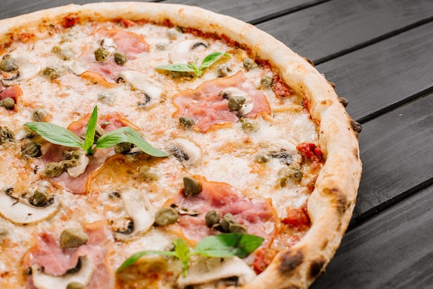 Leckere frische Pizza mit Zutaten auf Holzhintergrund