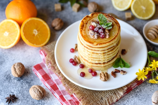 Leckere frische schöne Pfannkuchen mit Zitrushonig und Marmelade. Leckeres warmes Frühstück mit Pfannkuchen mit Obst und Beeren