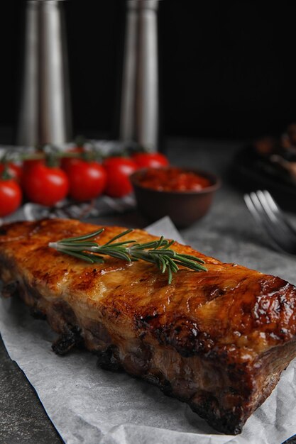 Leckere gegrillte Rippchen mit Rosmarin auf grauem Tisch