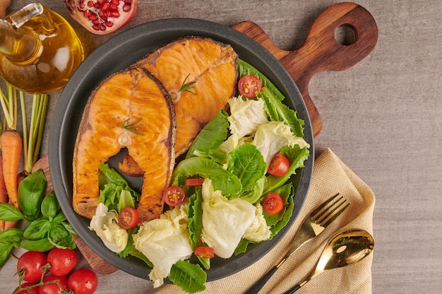 Leckere gekochte Lachsfischfilets. Gegrilltes Lachsfischfilet und frischer grüner Salatgemüsetomatensalat. Ausgewogenes Ernährungskonzept für eine saubere, flexible mediterrane Ernährung.