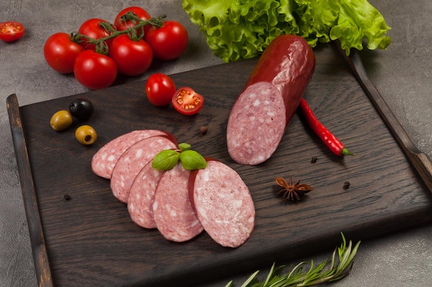 Foto leckere geräucherte wurstservelat oder salami auf dunklem holzhintergrund