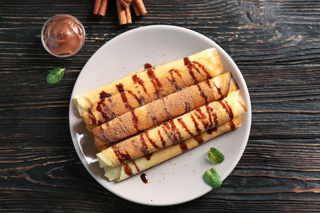 Leckere gerollte Pfannkuchen mit Schokolade auf Teller