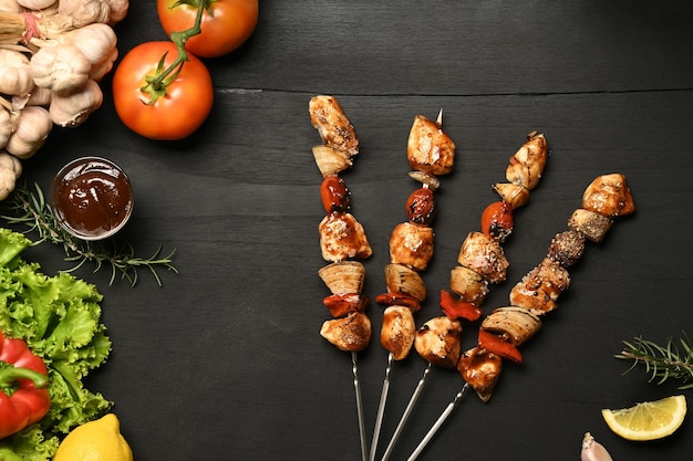 Leckere Grillspieße mit gegrillten Hähnchen-Kirschtomaten-Paprika-Zwiebeln und Barbecue-Sauce auf dunklem Steinhintergrund