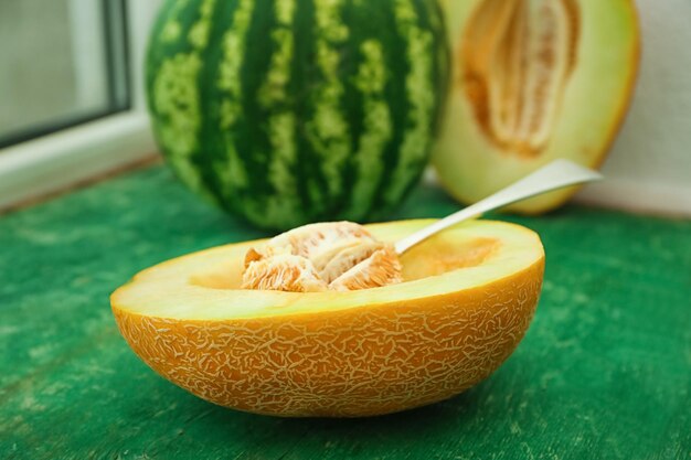 Foto leckere hälfte der melone und löffel mit samen auf holztisch