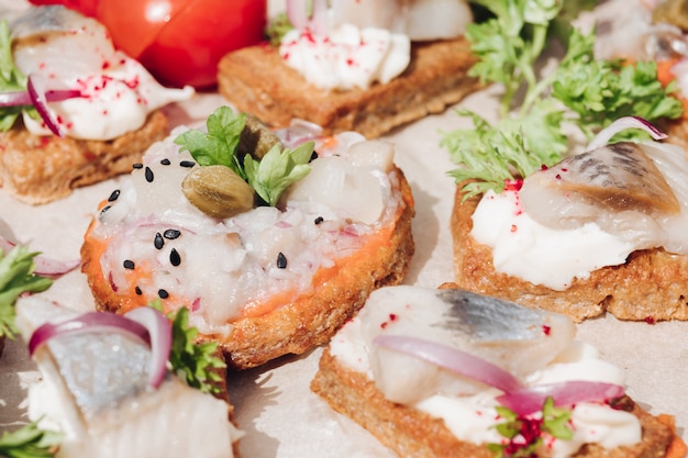 Leckere Häppchen mit Hering. Makro aus leckerem Häppchen oder Sandwiches mit frischem Hering, schwarzem Sesam, Frischkäse auf knusprigem Brot.