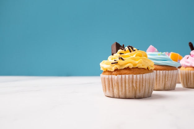 Leckere hausgemachte Cupcakes mit bunter Sahne und Belag mit Süßigkeiten und Schokoladenkeksen. Hausgemachte Herbstferien Nachtisch