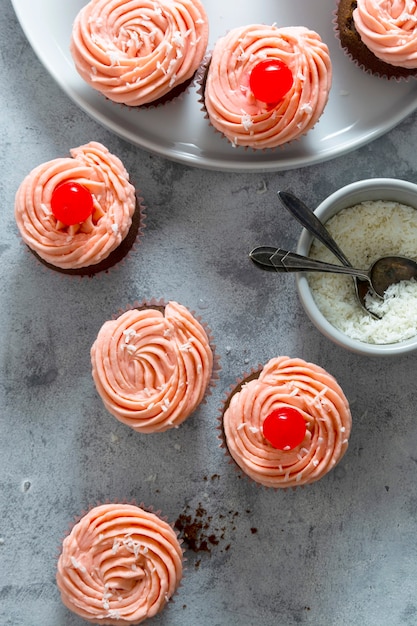 Leckere hausgemachte Cupcakes mit Schlagsahne und Kirsche