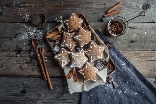 Leckere hausgemachte Kekse mit Gewürzlöffeln und lockigen Süßigkeiten, die auf einem Holztisch liegen