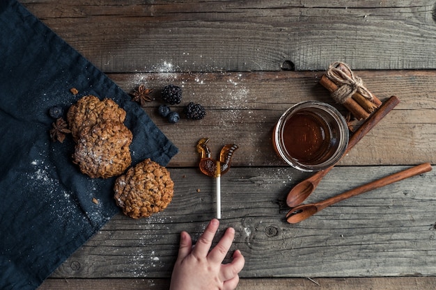 Leckere hausgemachte Kekse mit Gewürzlöffeln und lockigen Süßigkeiten, die auf einem Holztisch liegen