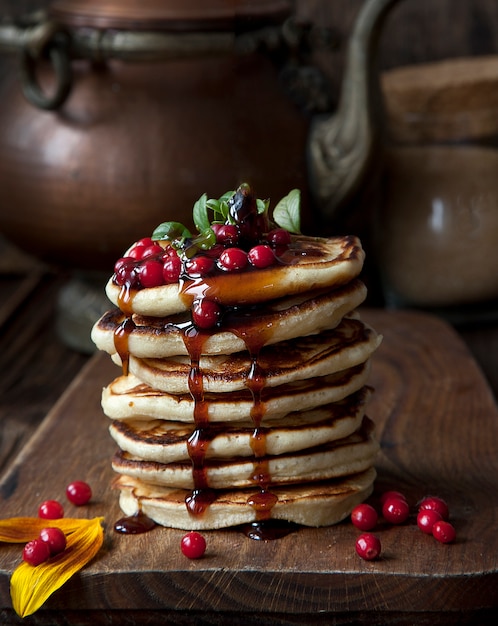 Leckere hausgemachte Pfannkuchen, Krapfen mit Honig und frischen Waldbeeren