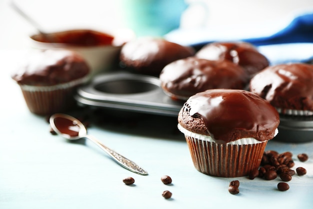 Leckere hausgemachte Schokoladenmuffins und eine Tasse Kaffee auf Holztisch auf hellem Hintergrund