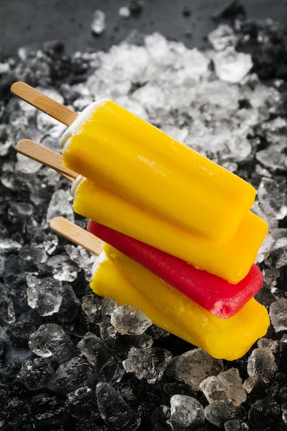 Leckere kalte frische appetitlich Eis auf Stick auf Eiswürfel auf dunklem Hintergrund. Nahansicht.