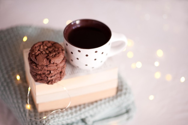 Leckere Kekse mit Tasse og Kaffee Nahaufnahme im Zimmer über Lichter auf der Rückseite. Guten Morgen. Frühstück. Wintersaison. Neujahr.