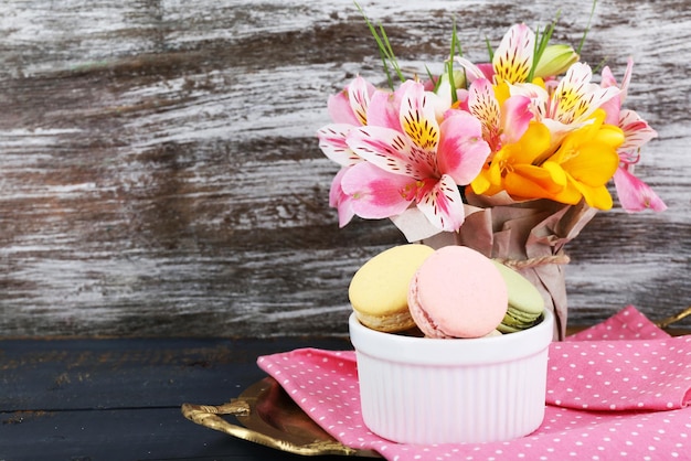 Leckere Makrone mit schönen Blumen auf Holzuntergrund