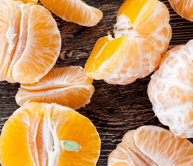 Leckere Mandarinen, geschälte Orangenschale auf einem Holztisch, gesunde Zitrusfrüchte mit vielen Vitaminen
