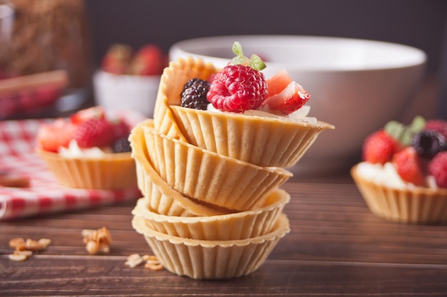 Leckere Mini-Torten-Törtchen mit frischen Beeren auf Holz