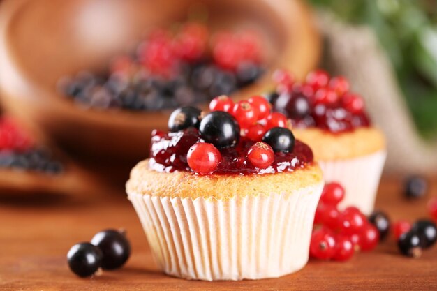 Leckere Muffins mit Beeren auf Holztisch