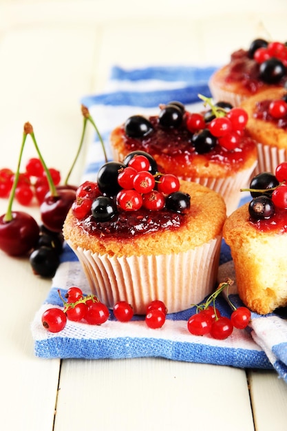 Leckere Muffins mit Beeren auf weißem Holztisch