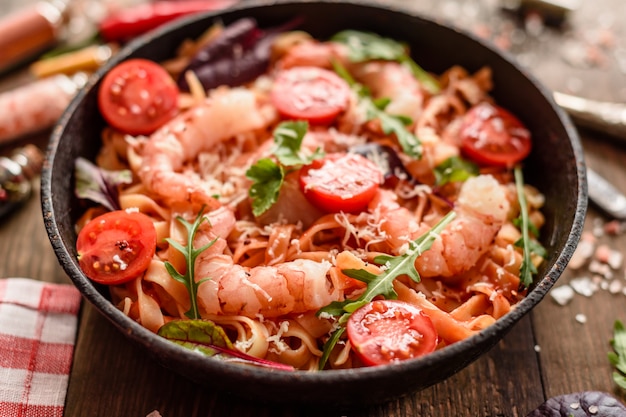 Leckere Nudeln mit Garnelen und Tomaten auf einer Pfanne