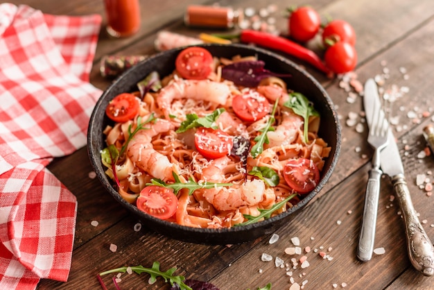 Leckere Nudeln mit Garnelen und Tomaten auf einer Pfanne