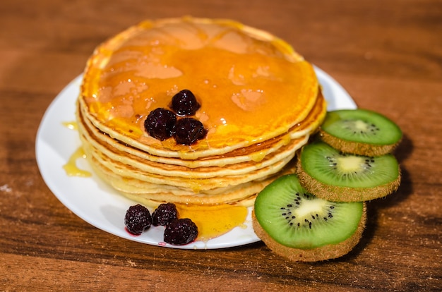 Leckere Pfannkuchen mit Honig, Kiwi und Beeren