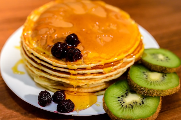 Leckere Pfannkuchen mit Honig, Kiwi und Beeren.