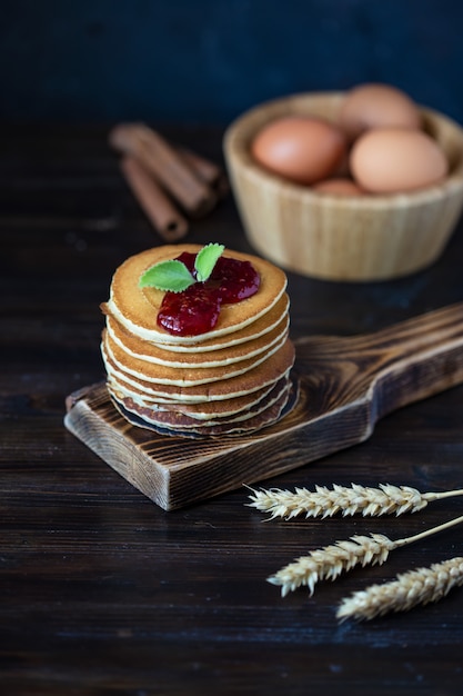 Leckere Pfannkuchen mit Marmelade und Minze auf einem dunklen Holztisch