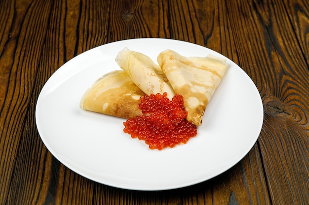 leckere Pfannkuchen mit rotem Kaviar auf einem Teller.