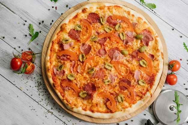 Leckere Pizza Chachatore mit Mozzarella, Salami und Oliven auf weißem Holzhintergrund