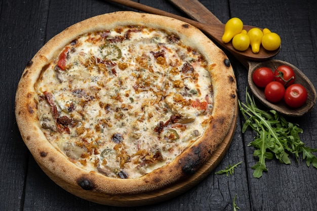 leckere pizza mit käse und gemüse auf einem dunklen holztisch