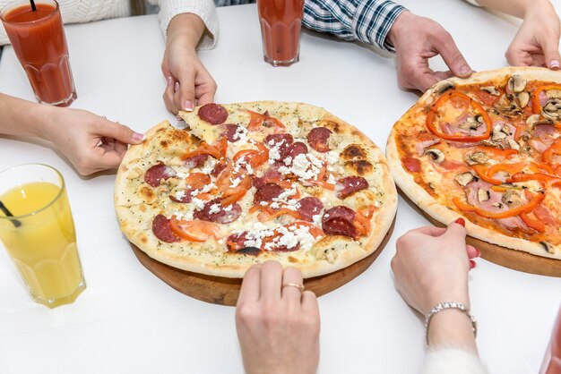 Leckere Pizza mit Menschenhänden auf dem Tisch hautnah