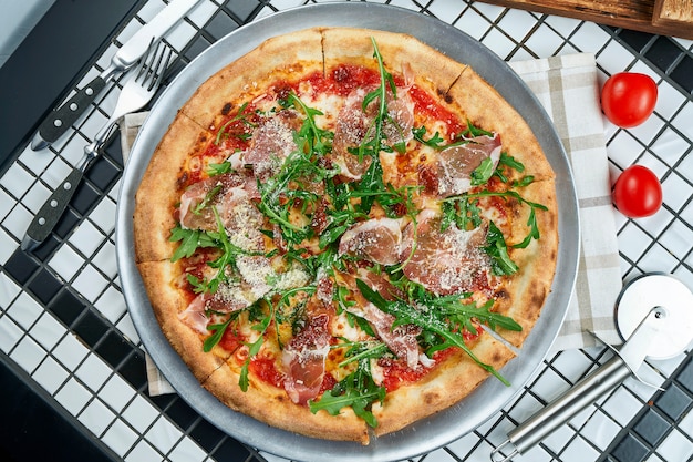 Leckere Pizza mit Parmaschinken, Rucola und Parmesan auf einem weißen Tisch. Italienische traditionelle Küche. Leckeres Essen flach liegen. Draufsicht