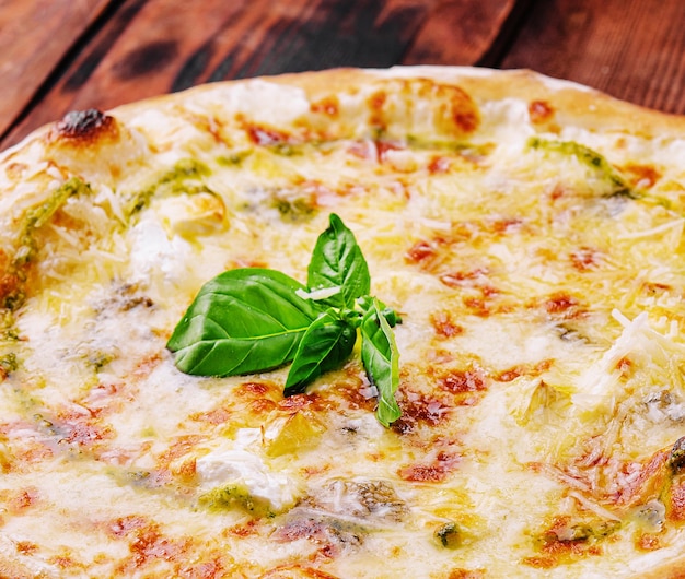 Leckere Pizza mit Pesto-Sauce auf Holzhintergrund