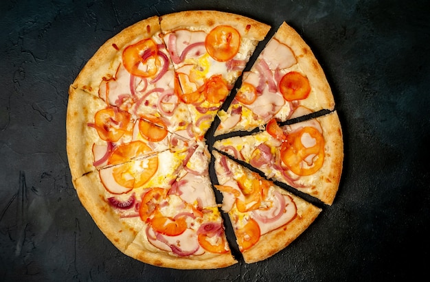 leckere Pizza mit Schinken, Tomate, Chili, Tomatensauce, Mozzarella auf Steinhintergrund