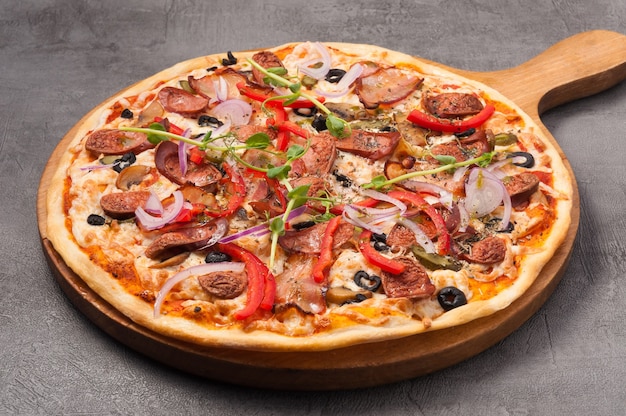Leckere Pizza mit Speck und Jagdwürsten auf grauem Hintergrund