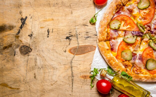 Leckere Pizza mit Speck und Tomaten auf einem Holztisch