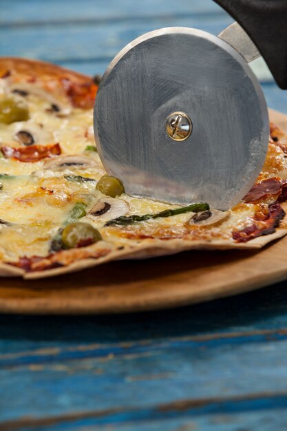 Leckere Pizza serviert auf Pizzatablett mit Cutter auf Pizza