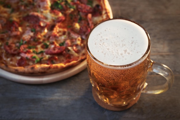 Leckere Pizza und ein Glas Bier stehen auf einem Holztisch