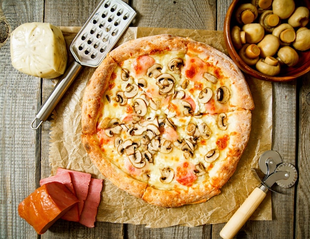 Leckere Pizza und Zutaten auf Holz