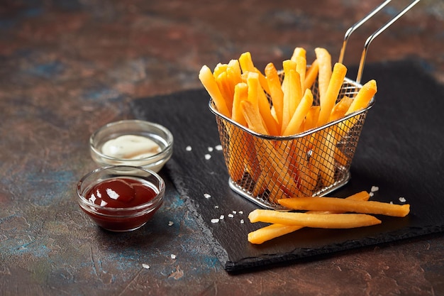 Leckere Pommes Frites auf Schneidebrett auf Holztischhintergrund